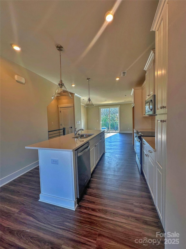 kitchen featuring appliances with stainless steel finishes, white cabinets, an island with sink, and dark wood-type flooring