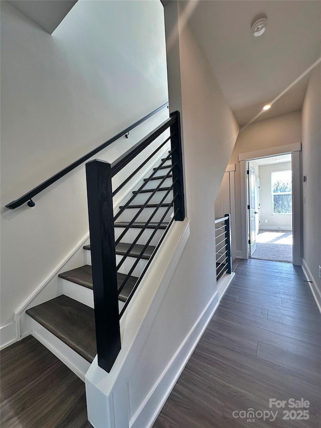 stairs with lofted ceiling, wood finished floors, and baseboards