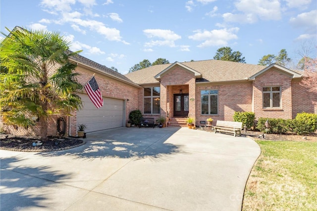 single story home with a garage, concrete driveway, brick siding, and roof with shingles