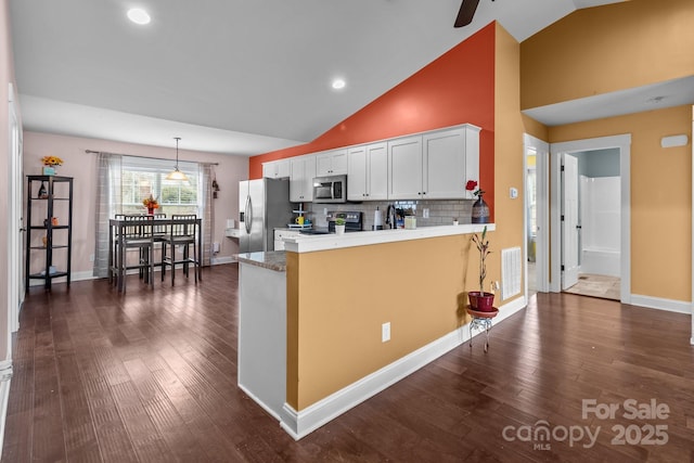 kitchen with light countertops, appliances with stainless steel finishes, dark wood-type flooring, white cabinets, and a peninsula