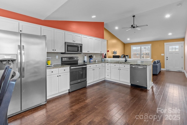 kitchen featuring appliances with stainless steel finishes, dark wood-style flooring, a peninsula, light stone countertops, and white cabinetry