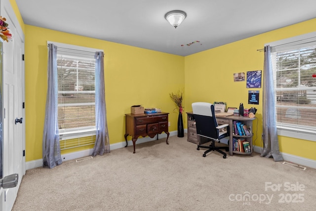 office area with a wealth of natural light, visible vents, light carpet, and baseboards