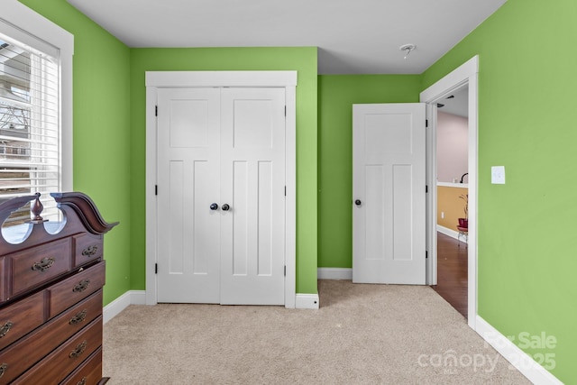 bedroom featuring a closet, light carpet, and baseboards