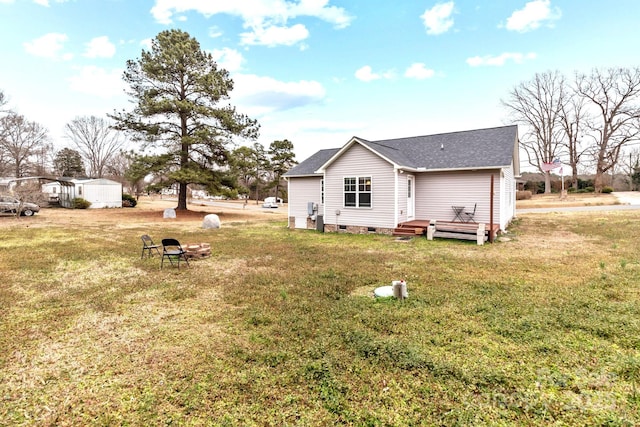 rear view of property featuring a yard, crawl space, and roof with shingles