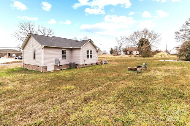 back of property featuring crawl space, central air condition unit, an outdoor fire pit, and a yard