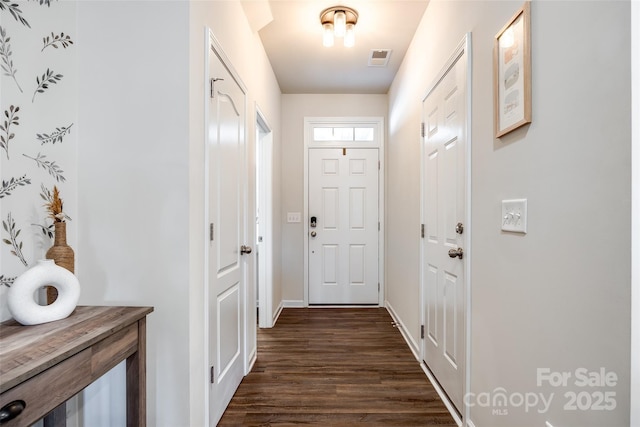 doorway featuring baseboards, visible vents, and dark wood-type flooring