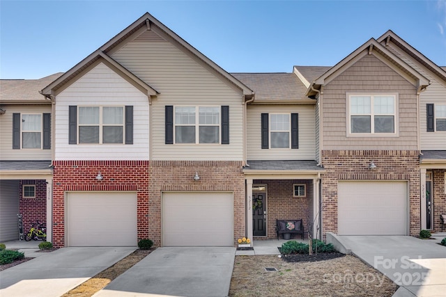 multi unit property with a garage, brick siding, driveway, and roof with shingles