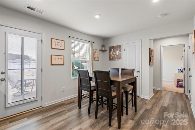 dining space with visible vents, baseboards, and wood finished floors