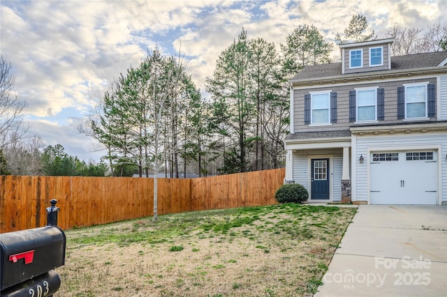 view of front of home with driveway, a front lawn, an attached garage, and fence