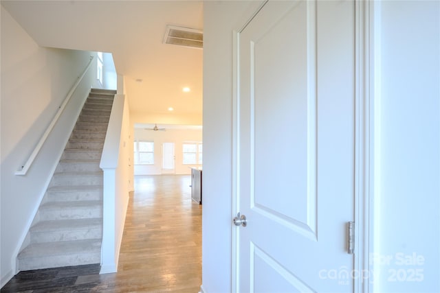 stairway featuring a ceiling fan, visible vents, wood finished floors, and recessed lighting