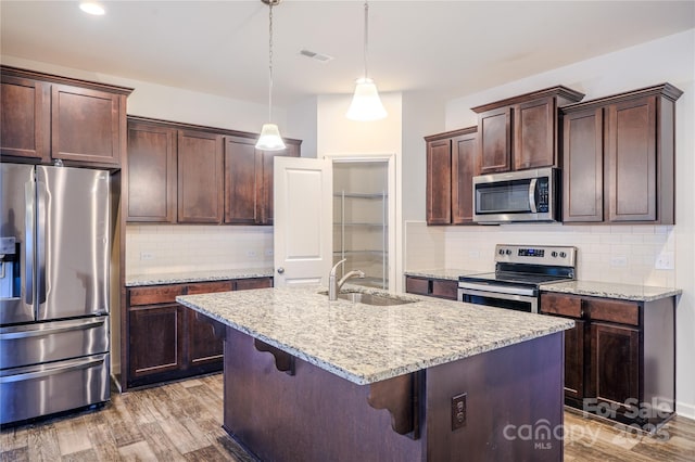 kitchen featuring dark brown cabinetry, visible vents, light wood-style flooring, appliances with stainless steel finishes, and a sink