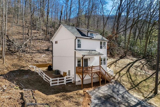 view of front of property with stairs, a shingled roof, fence, and central air condition unit