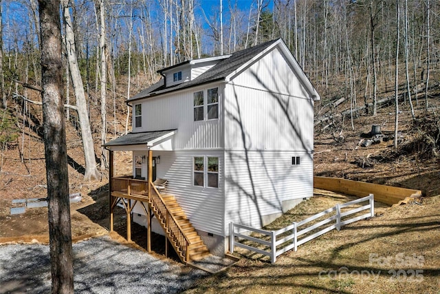 view of front of house with crawl space, roof with shingles, fence, and stairs