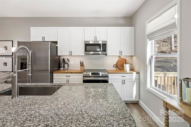 215 David Ridge Rd, Black Mountain, NC 28711 - kitchen with stone countertops, a sink, white cabinets, appliances with stainless steel finishes, and tasteful backsplash