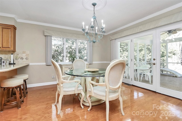 dining space featuring light wood-type flooring, an inviting chandelier, baseboards, and ornamental molding