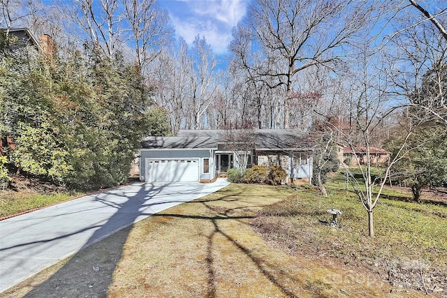 view of front of home with concrete driveway, an attached garage, and a front yard