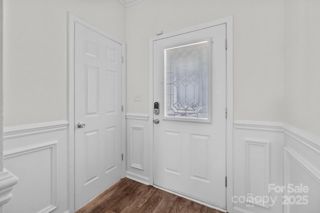 doorway to outside featuring dark wood-type flooring, a wainscoted wall, and a decorative wall