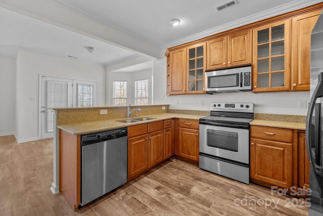 kitchen featuring appliances with stainless steel finishes, brown cabinets, visible vents, and a peninsula