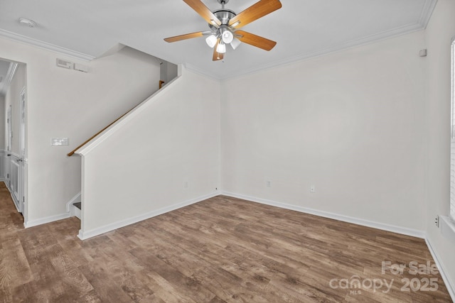 empty room with wood finished floors, a ceiling fan, baseboards, stairs, and crown molding