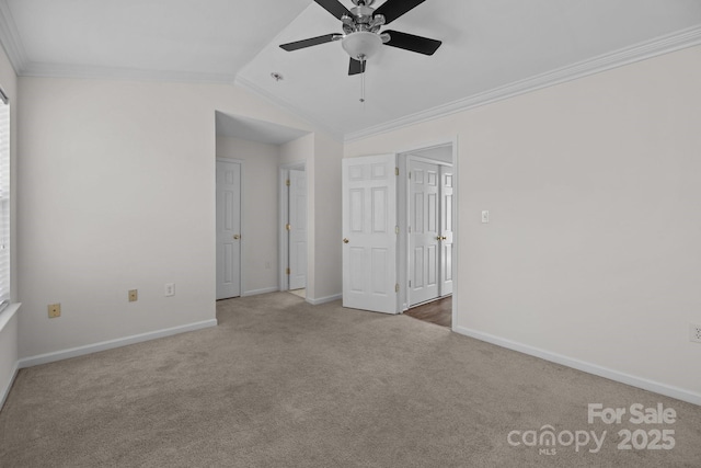 unfurnished bedroom featuring lofted ceiling, carpet, ornamental molding, and baseboards