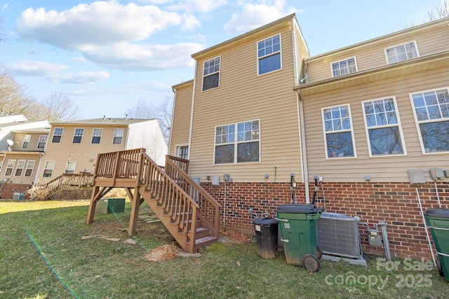 back of property with a wooden deck, stairway, a yard, central air condition unit, and brick siding