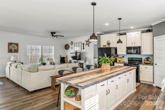 kitchen with pendant lighting, open floor plan, white cabinetry, a kitchen island, and black appliances