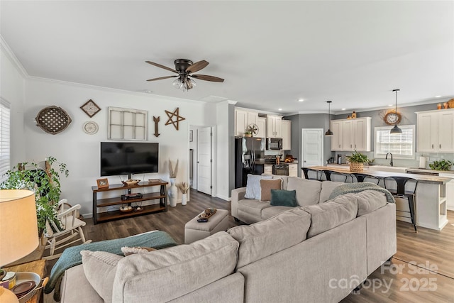 living room featuring baseboards, a ceiling fan, dark wood finished floors, and crown molding