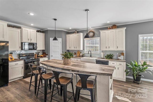 kitchen featuring black appliances, a kitchen island, a sink, and decorative light fixtures