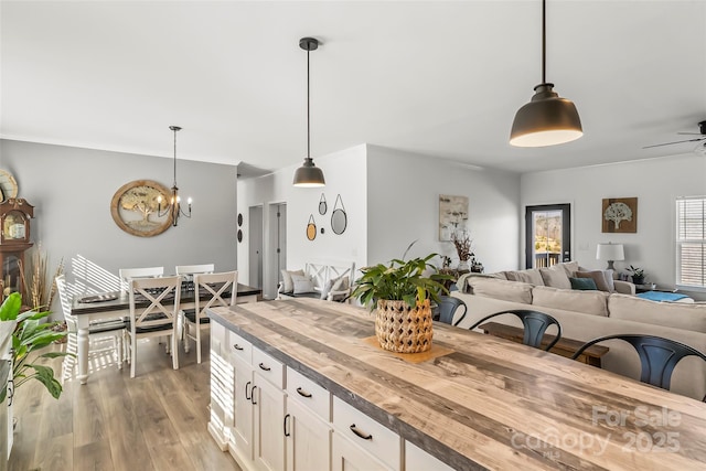 kitchen with open floor plan, hanging light fixtures, butcher block counters, and light wood finished floors