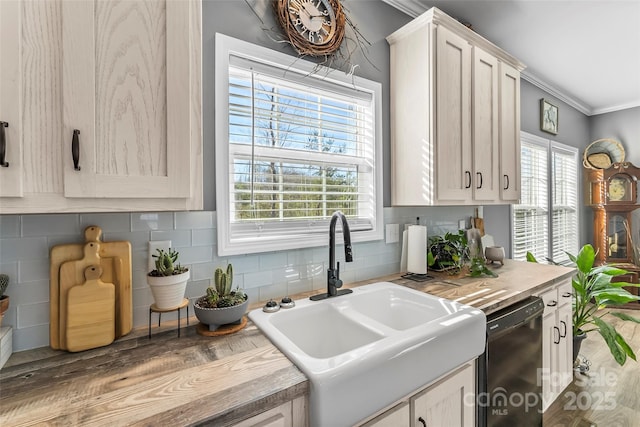 kitchen featuring a sink, black dishwasher, light countertops, decorative backsplash, and crown molding