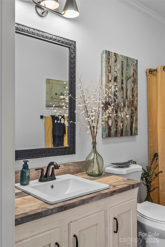 bathroom with ornamental molding, vanity, and toilet