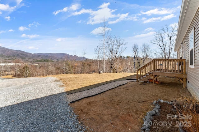 view of yard with a deck with mountain view and stairs