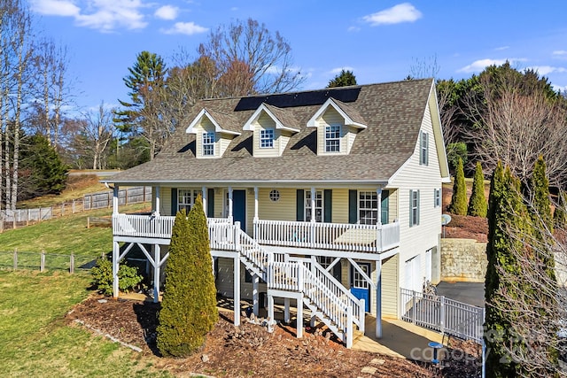 view of front of property featuring roof with shingles, a porch, stairway, an attached garage, and a front yard