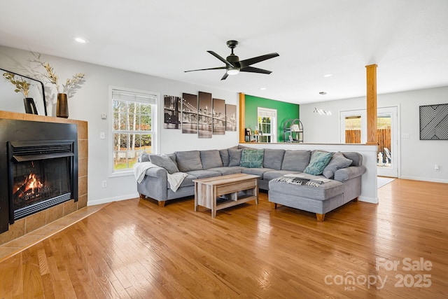 living room featuring ceiling fan, light wood-style flooring, recessed lighting, baseboards, and a tiled fireplace