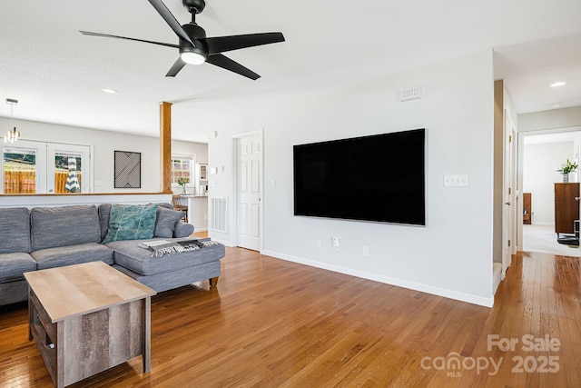 living area with a ceiling fan, baseboards, and wood finished floors