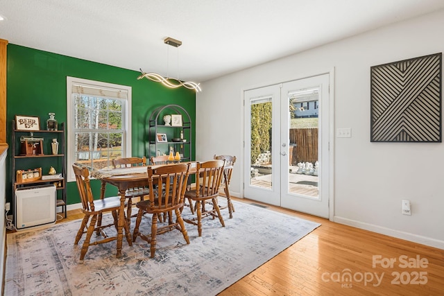 dining room with french doors, wood finished floors, visible vents, and baseboards