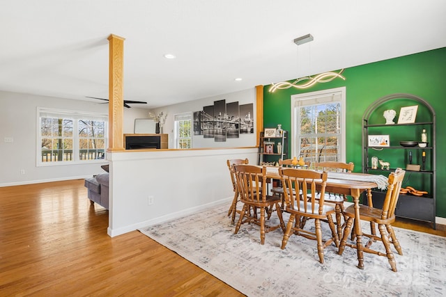 dining room with baseboards, ceiling fan, wood finished floors, a fireplace, and recessed lighting