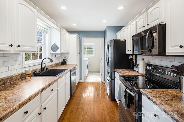 kitchen featuring electric range, a sink, and white cabinets