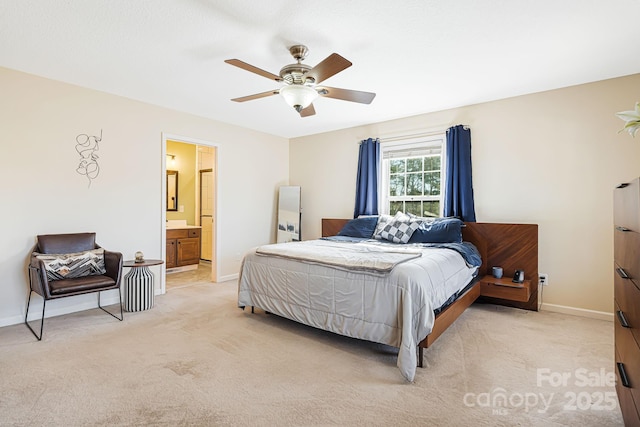 bedroom with baseboards, connected bathroom, a ceiling fan, and light colored carpet