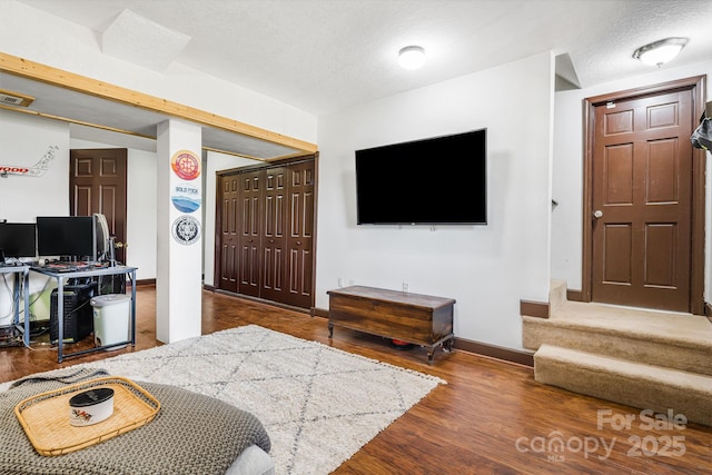 living room with a textured ceiling, wood finished floors, and baseboards