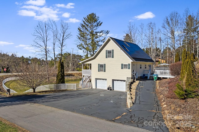 view of property exterior featuring an attached garage, a deck, stairway, and aphalt driveway