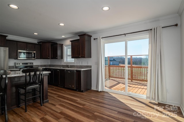 kitchen with crown molding, dark wood finished floors, stainless steel appliances, and light countertops