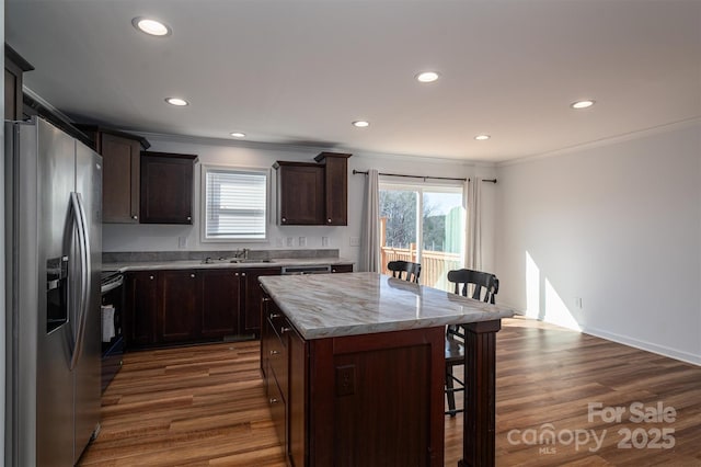 kitchen featuring a center island, dark wood-style flooring, range with electric stovetop, stainless steel fridge, and a kitchen bar