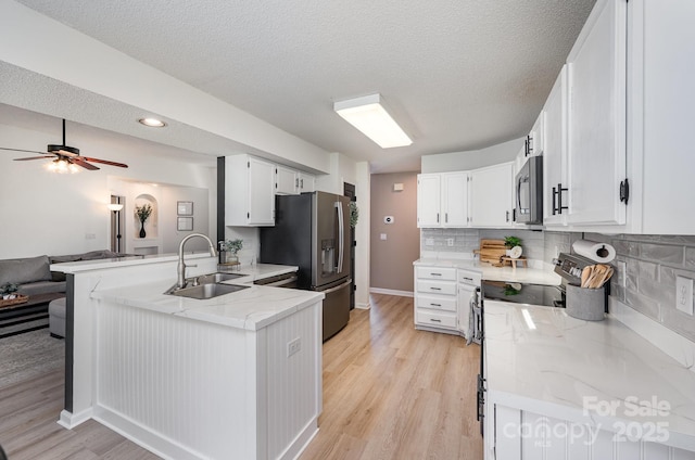 kitchen featuring a peninsula, light wood finished floors, stainless steel refrigerator with ice dispenser, and a sink