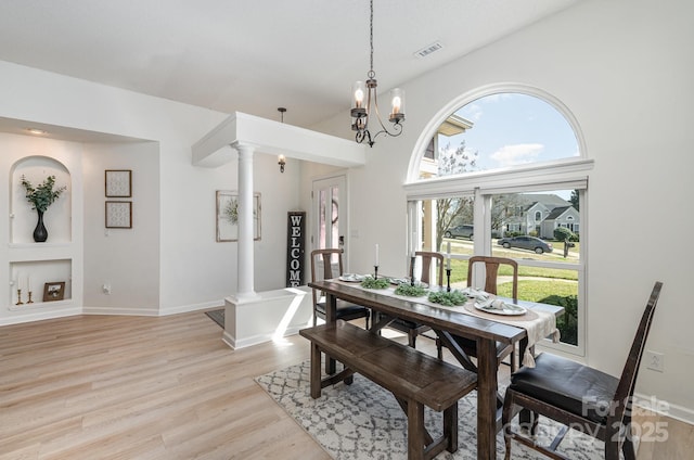 dining area featuring visible vents, a healthy amount of sunlight, decorative columns, and light wood-style floors