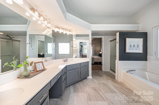 bathroom with a sink, a shower stall, a bath, and double vanity