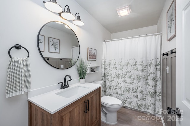 bathroom with toilet, a shower with shower curtain, wood finished floors, and vanity