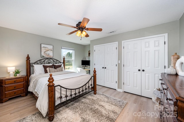 bedroom with visible vents, two closets, a ceiling fan, and light wood-style floors