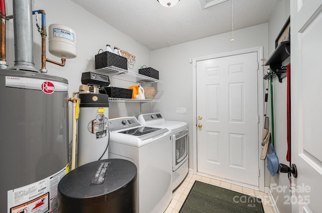 clothes washing area featuring water heater, attic access, a textured ceiling, laundry area, and independent washer and dryer