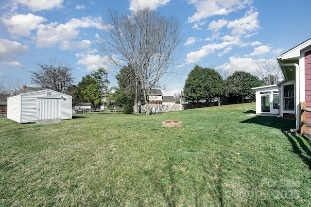 view of yard with a storage shed, an outdoor fire pit, fence, and an outbuilding